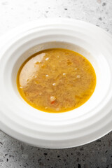 A close-up view of a warm, hearty soup served in a white bowl, featuring a rich texture and inviting color, perfect for food photography and culinary presentations.