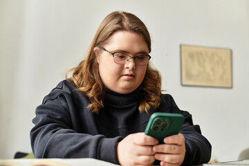 Young woman with Down syndrome enjoys a relaxed moment at home while using her phone