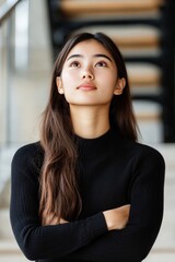 Fototapeta premium Confident woman with long dark hair standing arms crossed against light neutral background showing assertiveness modern femininity and strong personal identity in clean style
