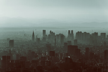 Aerial view of Tokyo skyline with a vintage film effect, where skyscrapers emerge through layers of mist, blending into distant mountains in the background