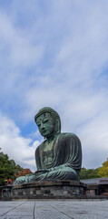 Fototapeta premium Vertical composition of the Great Buddha in Kamakura Japan captured from below showcasing the grand scale of the bronze statue with a dominant sky