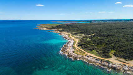 This stunning aerial photo captures the picturesque coastline near Medulin, Istria with crystal-clear turquoise waters, rocky shores, and dense forests. Trail 333 in Ližnjan runs along this coast