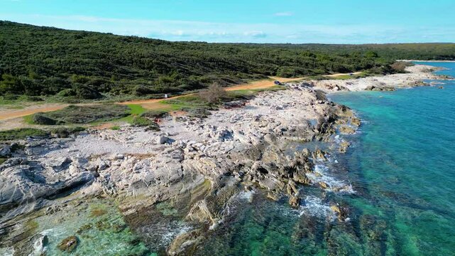 This stunning aerial photo captures the picturesque coastline near Medulin, Istria with crystal-clear turquoise waters, rocky shores, and dense forests. Trail 333 in Ližnjan runs along this coast