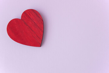 Fototapeta premium Red wood heart on the pink fabric background with space for text.