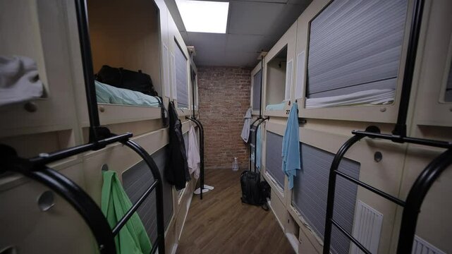 Rows of capsule beds in modern hostel dormitory with brick wall