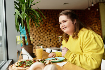 Young woman enjoying a casual meal in a cozy cafe while radiating confidence and joy