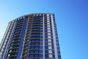 Fototapeta premium A tall building stands out against a clear, bright blue sky