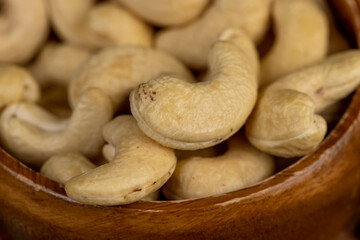 large cashew nuts are scattered on a larch board