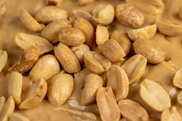 peanut butter on a piece of bread and roasted peanuts on the table