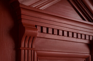 Close-up of a restored door with carved decor and massive brackets with chamfer. The rich color...