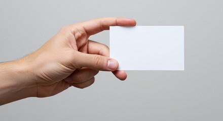 Fototapeta premium Blank Business Card in Hand: A hand delicately presenting a blank business card, ready for your message. perfect for showcasing your brand and content.