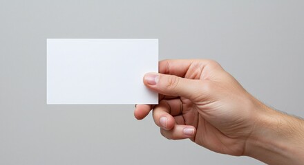 Fototapeta premium Holding Blank Card: A hand delicately holds a blank card. Perfect for design mockups, business presentations, and minimalist concepts.