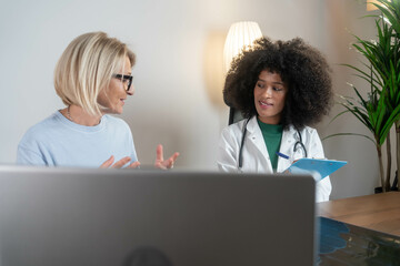 medicine, healthcare and people concept - female african american doctor with clipboard talking to...