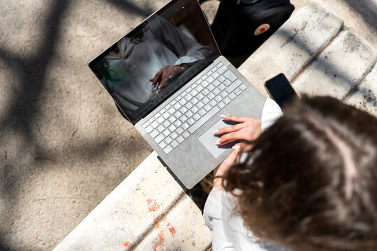 Trader woman working on laptop outdoors, managing investments and finances