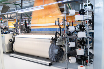 Industrial fabric production line. A loom at a textile factory. Fabric making process