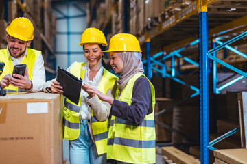 Team Collaborating in Warehouse on Digital Devices While Wearing Safety Gear