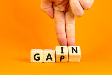 Gain or gap symbol. Concept words Gain Gap on wooden block. Beautiful orange table orange background. Businessman hand. Business gain or gap concept. Copy space.
