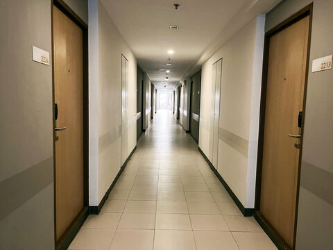 Modern condominium hallway with wooden doors and clean minimalist design, Residential apartment corridor with bright lighting and tiled floor, corridor in a hotel