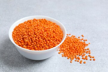 Red lentils in a bowl on a gray background