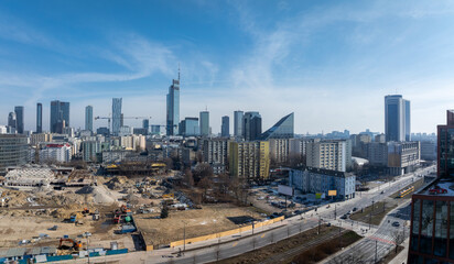 Aerial view of Warsaw, Poland, featuring Varso Tower, Warsaw Spire, high rise buildings, mid century blocks, a construction site, and busy streets.