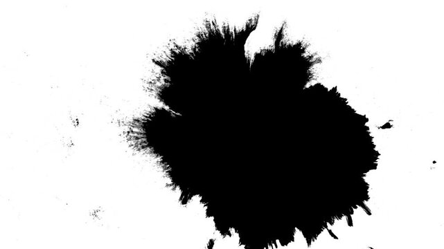 Spraying black paint on a white background. Spray of ink over the white surface. Black watercolor paint spraying. Particles of black paint scatter on white paper.