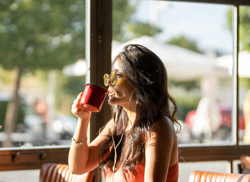 Woman Enjoys Coffee in Sunlit Cafe, Relaxing Moment Captured