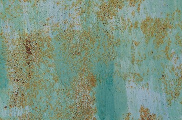 Rusty turquoise paint peeling off an exterior wall with textured surface and weathered appearance...