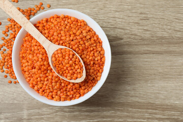Red lentils in a bowl on a wooden background
