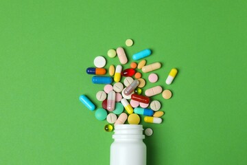 Various pills with white bottle on color background, top view