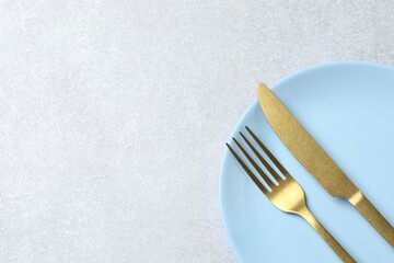 Blue empty plate with cutlery on a gray background