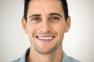 Obraz premium Close up cropped view happy Latin man having handsome appearance and optimistic mood, exuding confidence, smiling, revealing perfect-white teeth look at camera standing against grey wall background