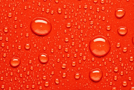 Water droplets on vibrant red surface creating textured art
