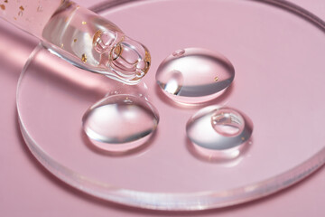 24K gold serum drops in a petri dish on a pink background