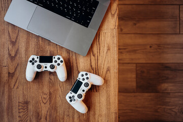 Gaming setup with laptop and controllers on wooden desk