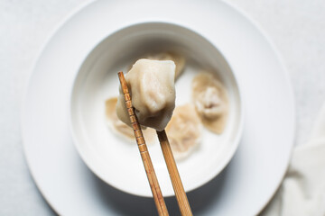 Overhead view of wontons in chopsticks, top view of soup wontons being eaten with chopsticks