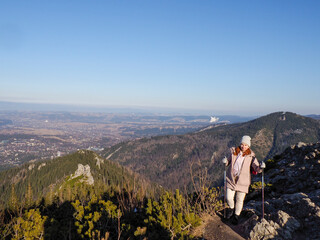Naklejka premium Solo Traveler in Light Clothing Standing on Rocky Mountain Summit Admiring Breathtaking Valley View in Clear Weather