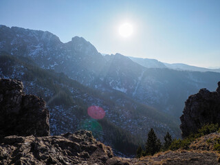 Dramatic Mountain Ridge Silhouette with Bright Sun Casting Golden Light through Rocky Peaks and...