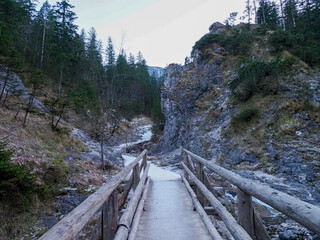 Rustic Wooden Bridge Crossing Mountain Stream in Secluded Forest Canyon