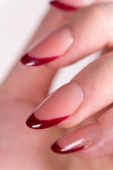 Naklejka premium Red French tips with a fine layer of glitter – a classic look that always appears sophisticated and elegant on a white background. Nails with a smooth nude base and glossy red tips.