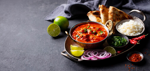 Indian curry, chicken tikka masala with rice and naan bread. Dark background. Copy space.