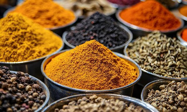 A vibrant array of spices in metal bowls, showcasing rich colors and textures, creating an inviting culinary experience