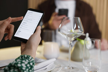 Couple choosing dishes from digital menu at restaurant, closeup