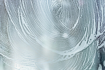 soap foam pattern wipe marks on window glass, window cleaning , blue background