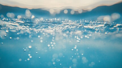 Blurred image of a clear blue water surface with ripples and bubbles. 