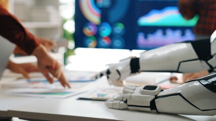 A futuristic business meeting scene featuring a robot arm collaborating with humans over data analysis and strategy planning in a modern office setting.Noogenesis