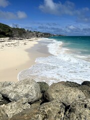 Gentle waves lap the warm sand of Crane Beach on the rugged east coast of Barbados on a beautiful sunny day.