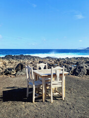 Square table and wooden chairs outdoors by the sea. Dining, leisure time by the sea.