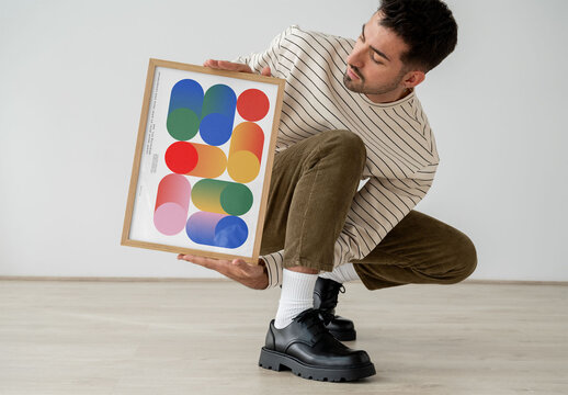 Mockup Of Man Crouching With Framed Customizable Poster