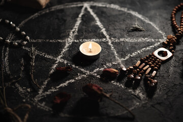 Black magic ritual with pentagram symbol, burning candles and amulets
