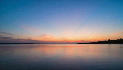 Obraz premium Serene sunset reflection over calm lake waters 